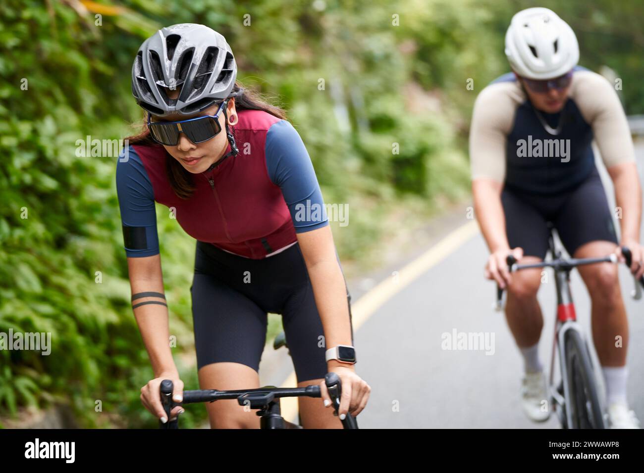giovani atleti di ciclismo asiatici che cavalcano in bicicletta all'aperto su strade rurali Foto Stock