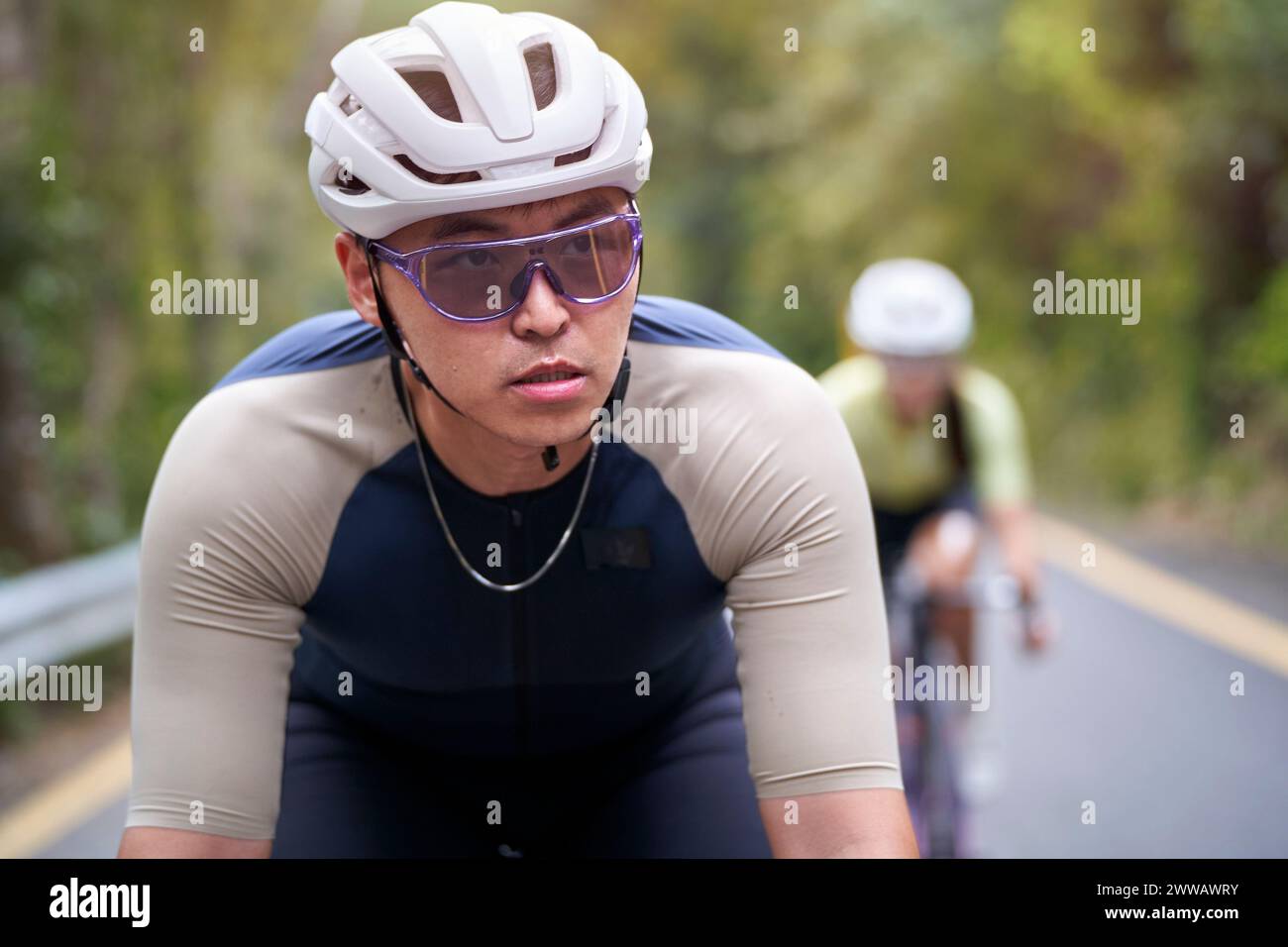 giovane uomo asiatico ciclista maschio che cavalca in bicicletta all'aperto su strada rurale Foto Stock