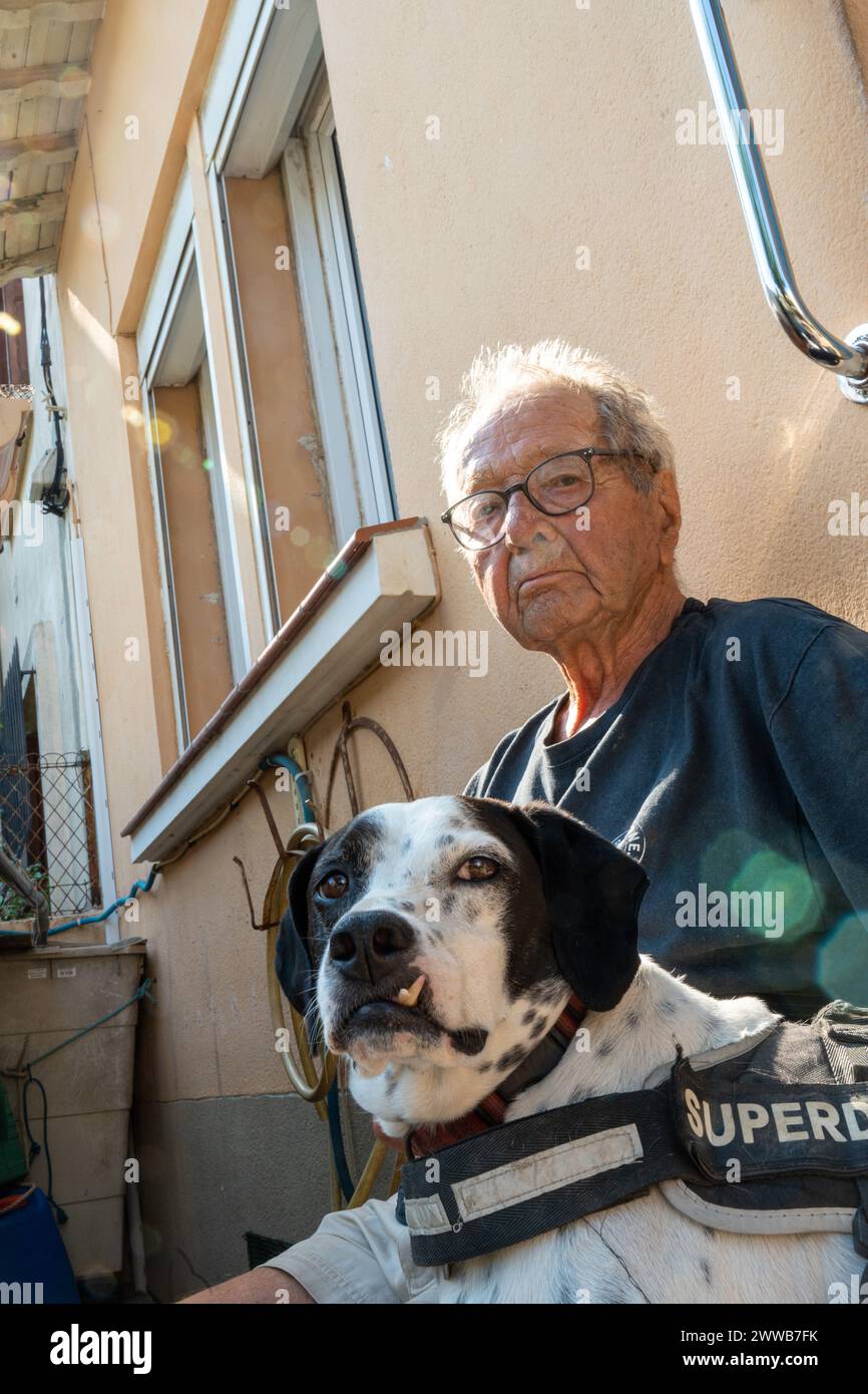 90 anni più anziano con il suo cane al sole davanti a casa sua. Foto Stock