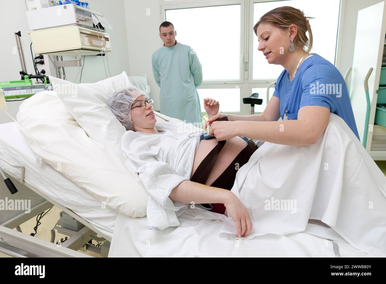 Ostetrica che mette in atto la festa nella sala parto. Implementazione di un monitoraggio che monitorerà le costanti del feto. Foto Stock