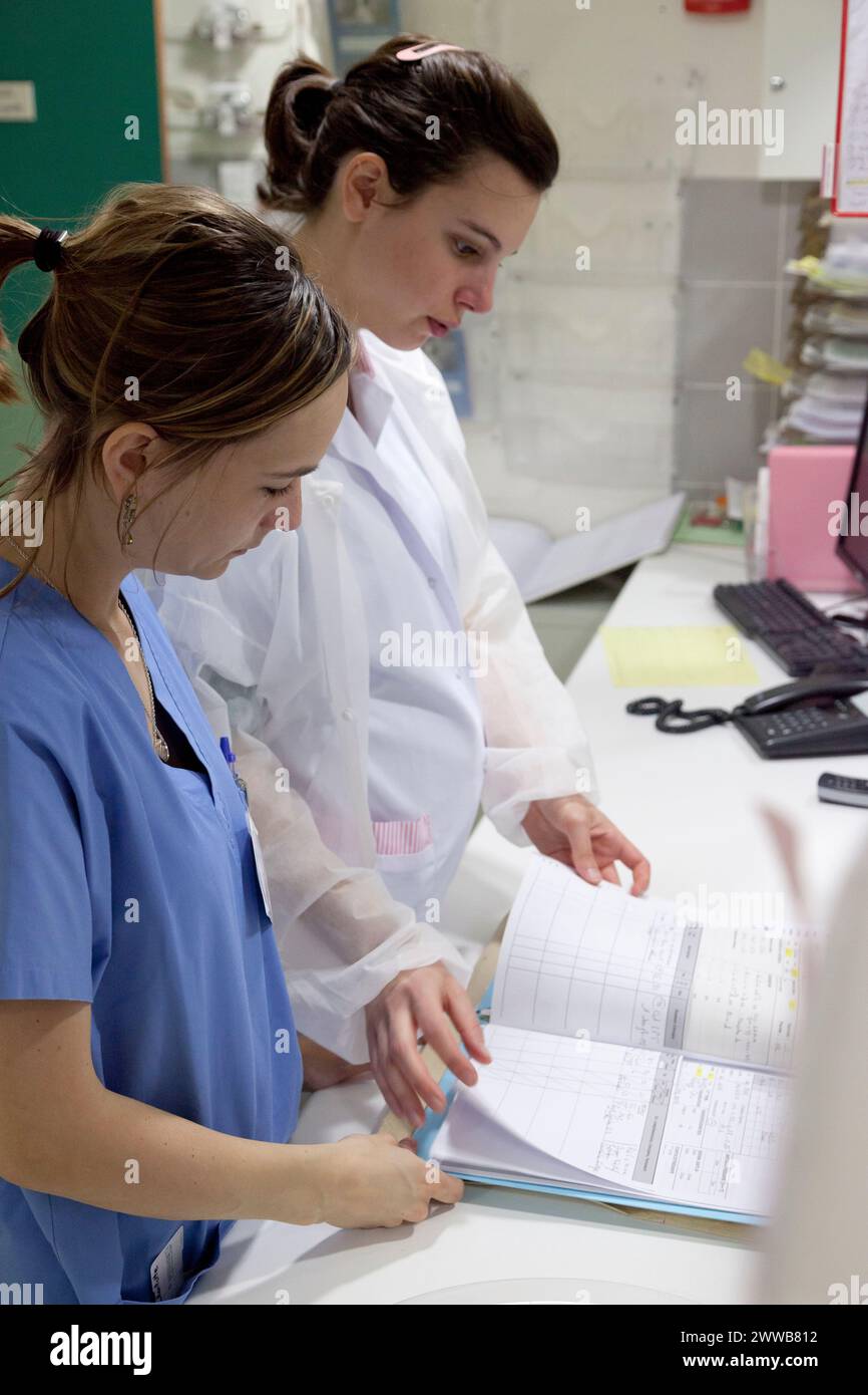 Ostetrica del pronto soccorso che presenta il file di un nuovo parturiente ad una ostetrica del blocco ostetrico. Foto Stock