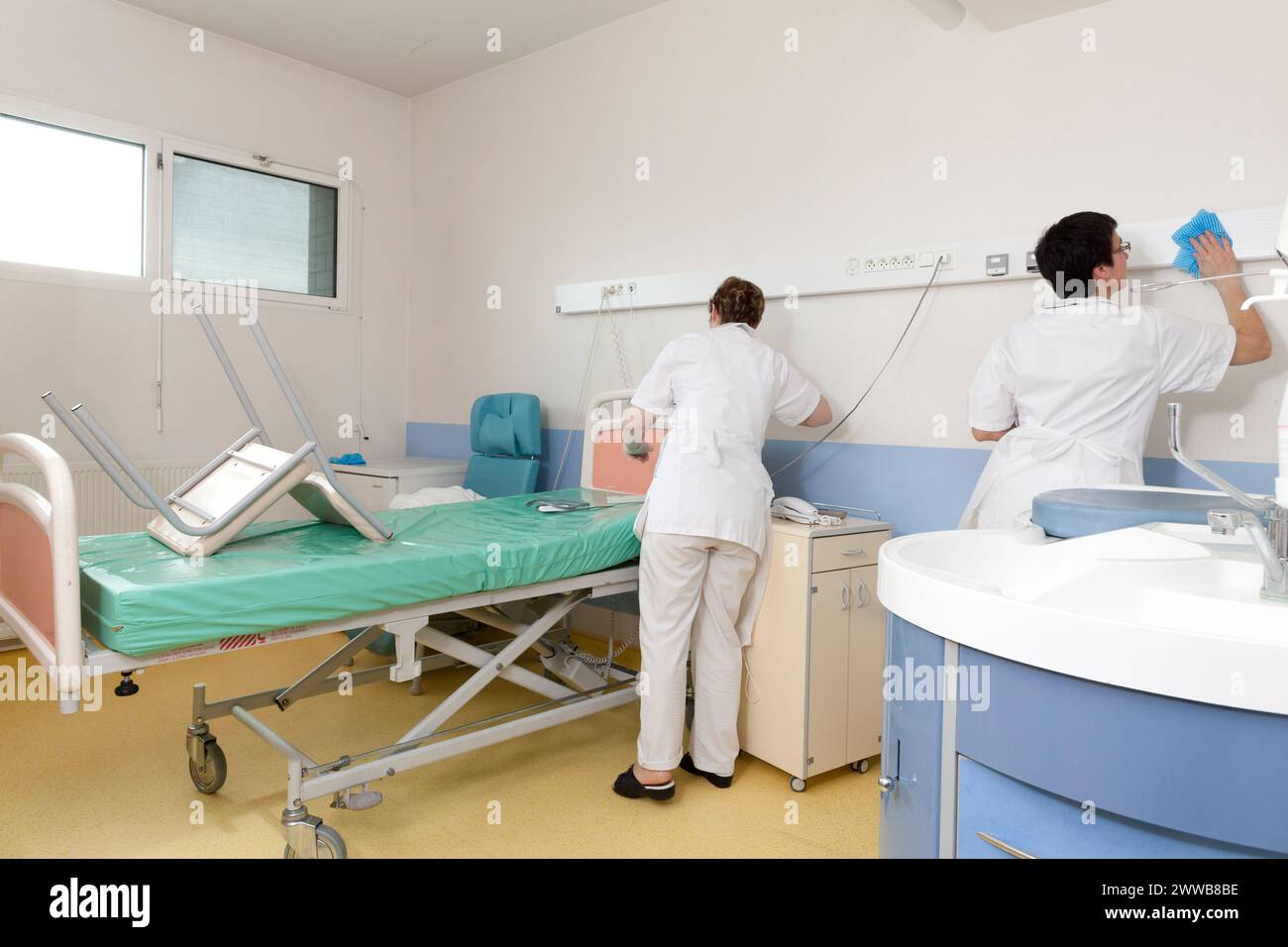Assistenti di assistenza all'infanzia che puliscono una stanza dopo che un paziente lascia la suite di pannolini. Foto Stock