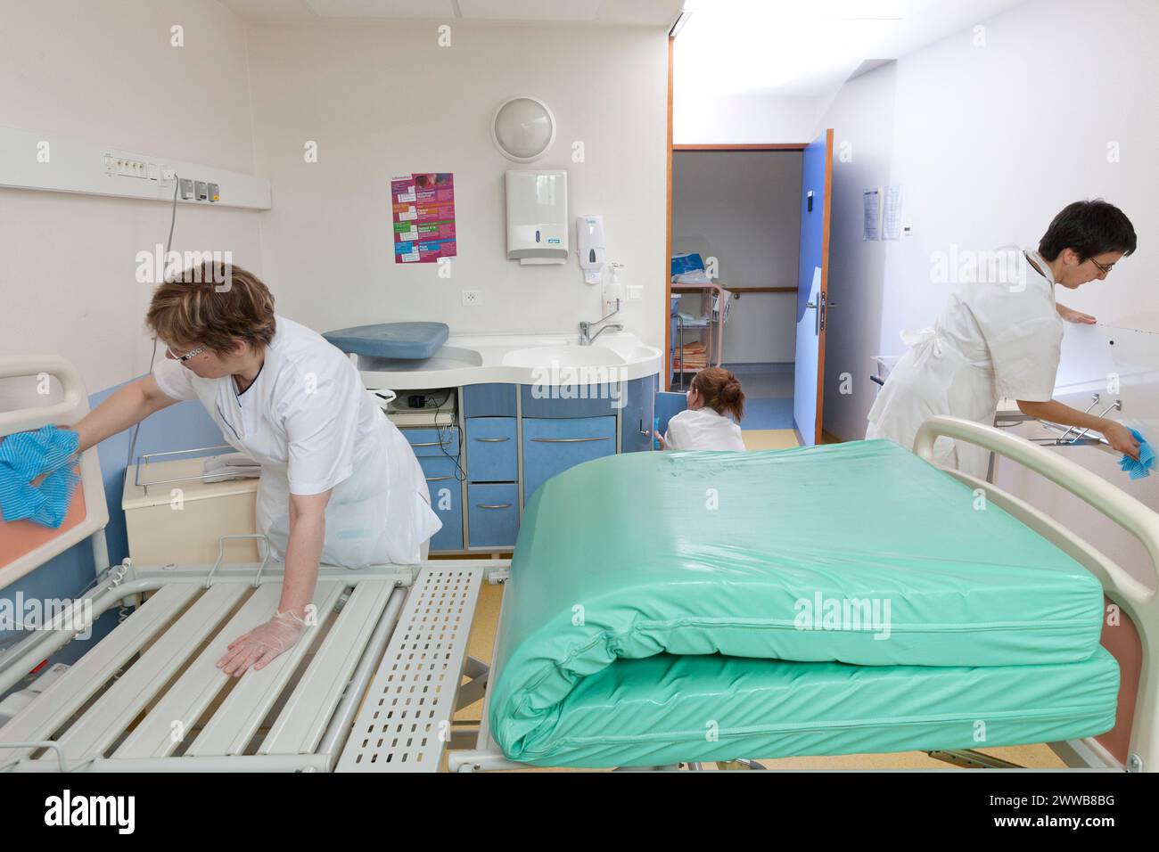 Assistenti di assistenza all'infanzia che puliscono una stanza dopo che un paziente lascia la suite di pannolini. Foto Stock