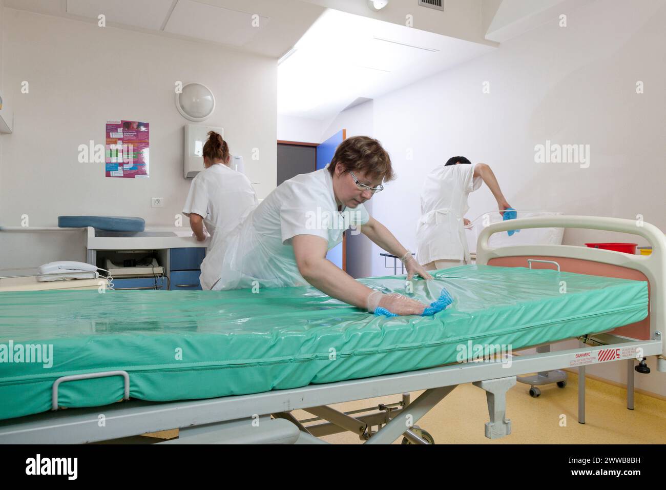 Assistenti di assistenza all'infanzia che puliscono una stanza dopo che un paziente lascia la suite di pannolini. Foto Stock