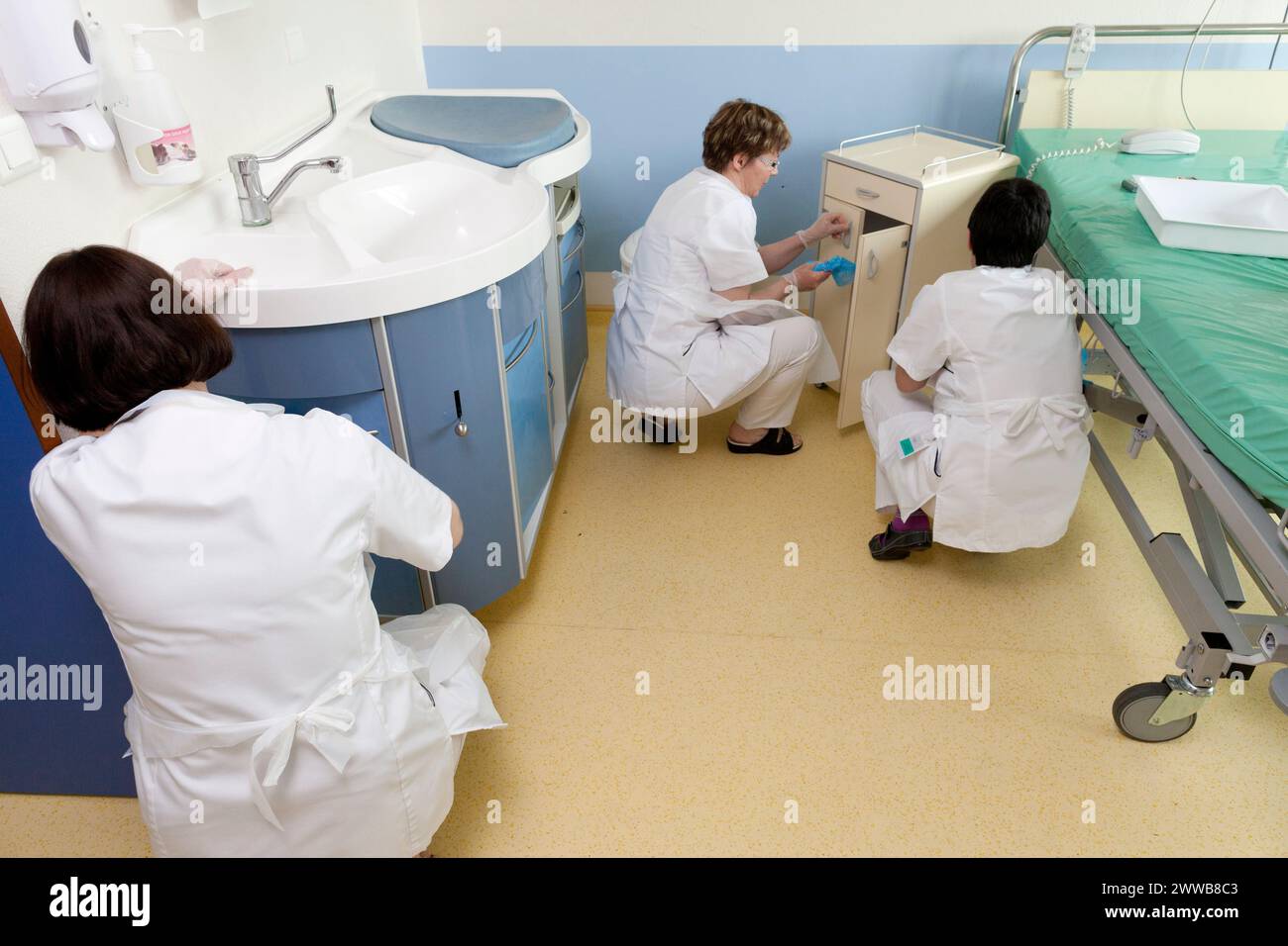 Assistenti di assistenza all'infanzia che puliscono una stanza dopo che un paziente lascia la suite di pannolini. Foto Stock
