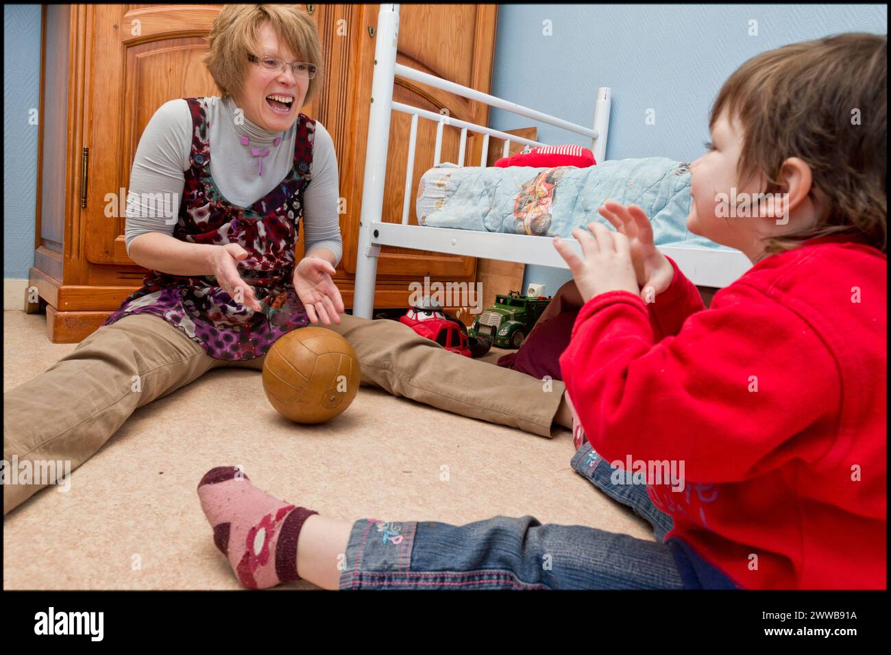 ASE - assistenza sociale infantile. Isabelle sta giocando a palla con Sarah sul pavimento della stanza dei ragazzi. SOLO PER USO EDITORIALE. Foto Stock