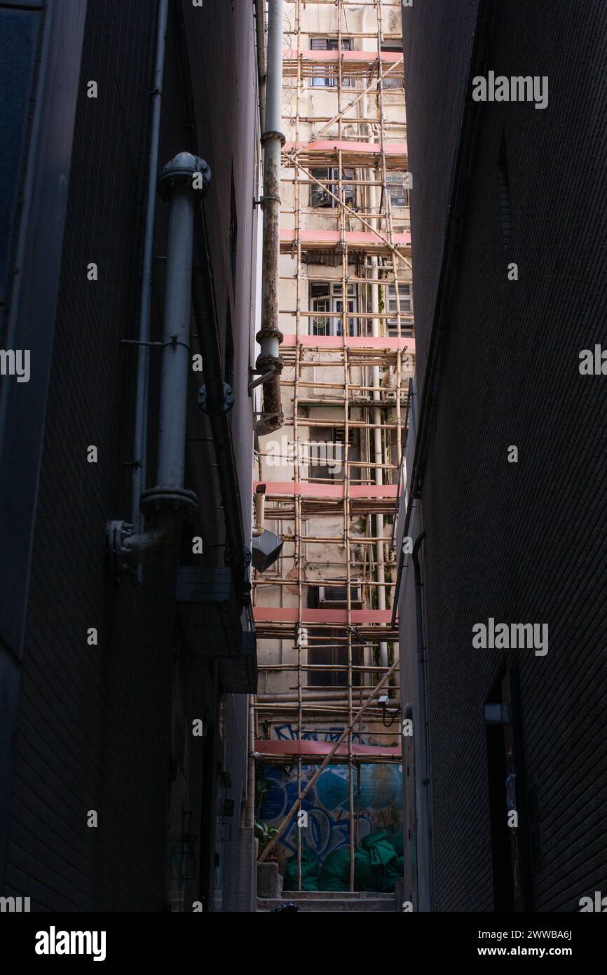 Una fetta della vita cittadina di Hong Kong mostra impalcature di bambù che coprono l'esterno di un condominio. Foto Stock