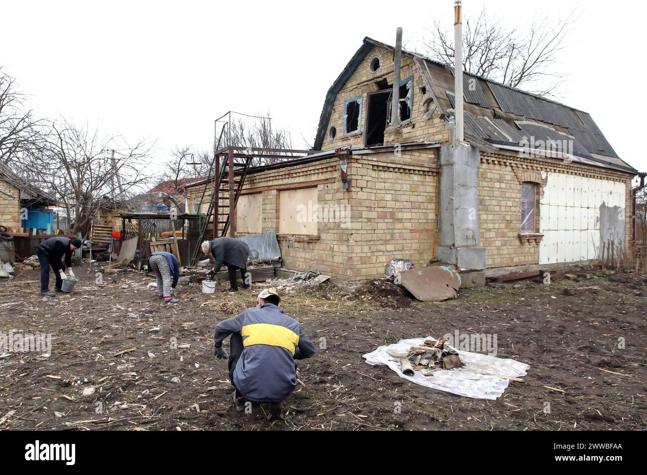 REGIONE DI KIEV, UCRAINA - 21 MARZO 2024 - le persone raccolgono detriti nel cortile di una casa danneggiata da un attacco missilistico russo, Hatne, regione di Kiev, Ucraina settentrionale. Foto Stock