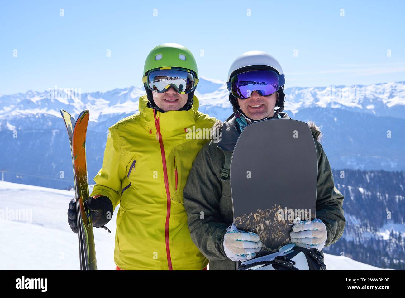 Due amici con attrezzatura da sci e snowboard che si godono una giornata di sole sulle montagne innevate. Foto Stock