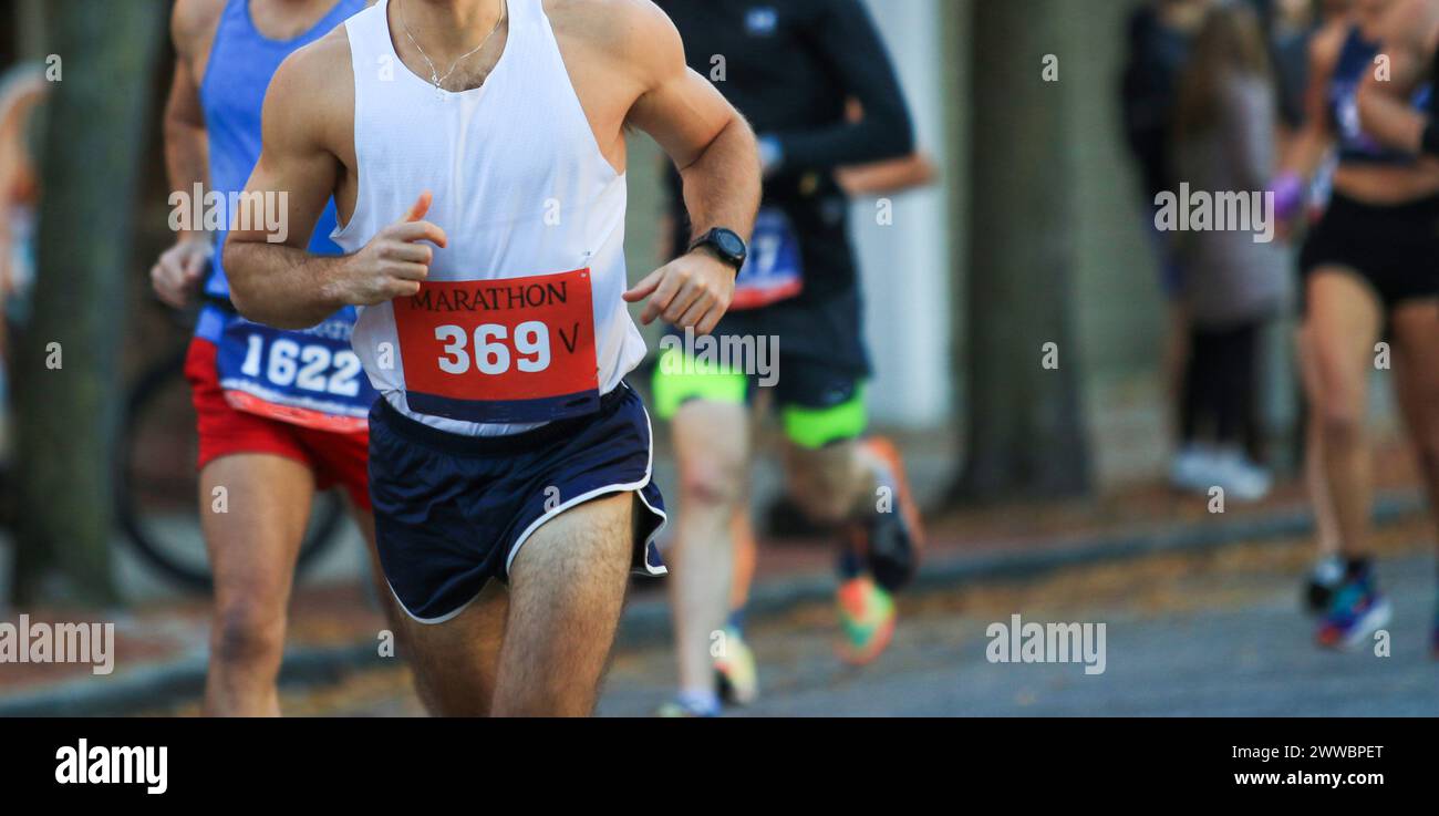 Corridori su strada che indossano bavaglino durante una maratona. Foto Stock