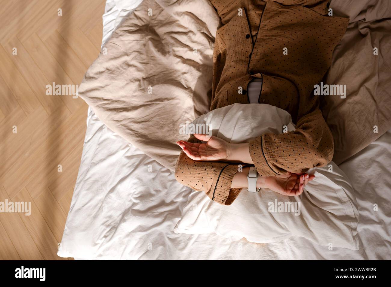 Persona che dorme con smartwatch. La donna non ha dormito abbastanza e si nasconde dai raggi del sole in camera da letto con cuscino. Foto Stock