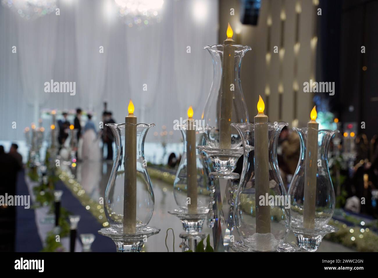 Candele in candelabri sullo sfondo di persone sfocate nella sala per matrimoni Foto Stock