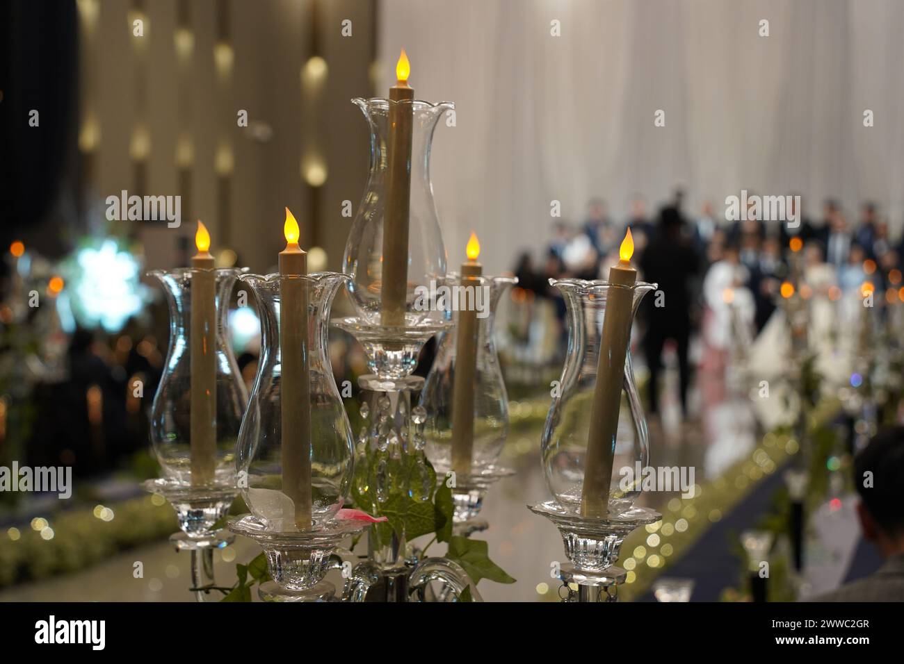 Candele in candelabri sullo sfondo di persone sfocate nella sala per matrimoni Foto Stock