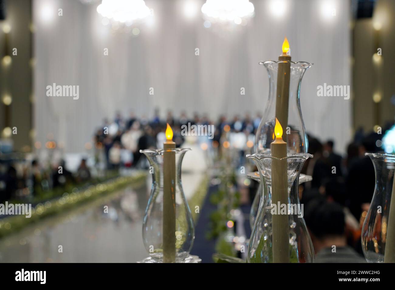 Candele in candelabri sullo sfondo di persone sfocate nella sala per matrimoni Foto Stock