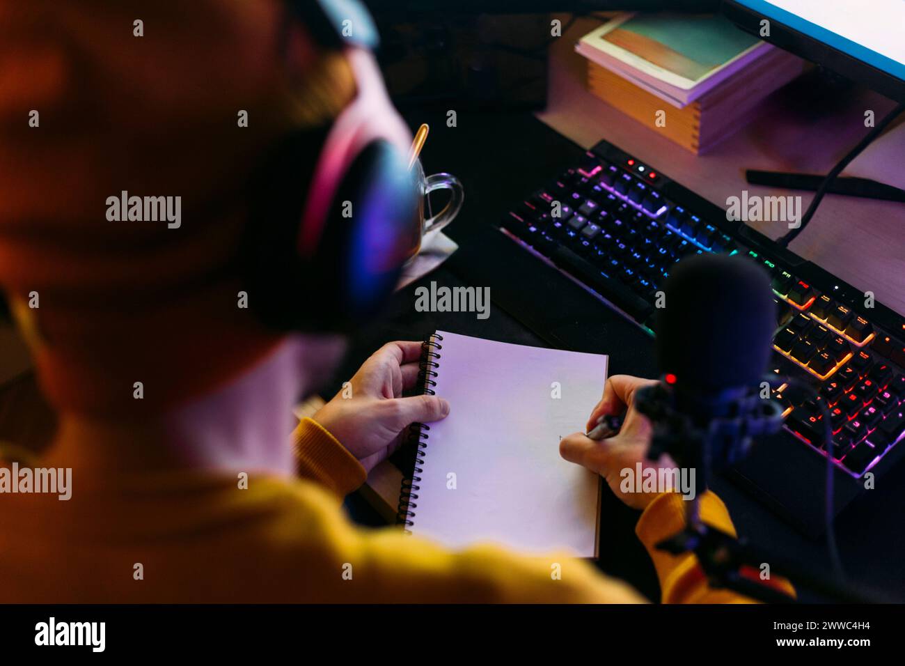L'influencer scrive su un blocco note vicino alla tastiera alla scrivania Foto Stock