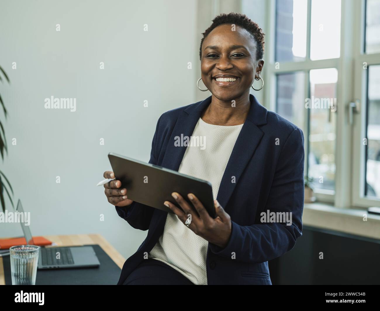 Donna d'affari sorridente che tiene un tablet PC in ufficio Foto Stock