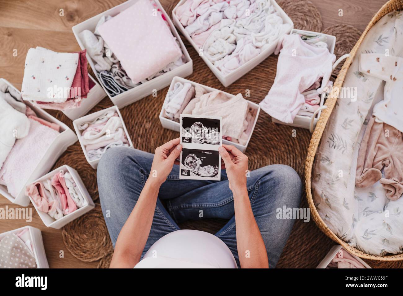 Donna incinta seduta sul pavimento e con fotografie a ultrasuoni a casa Foto Stock