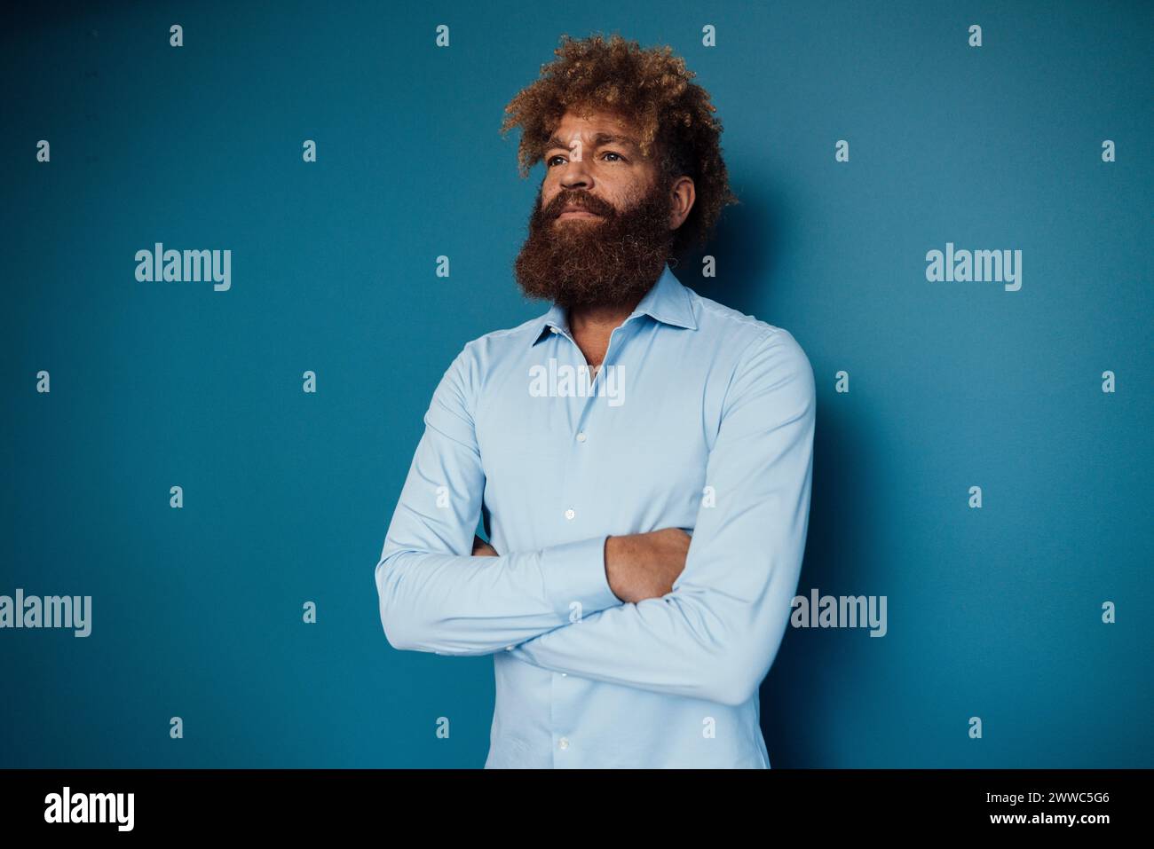 Uomo maturo che indossa una camicia blu e si trova davanti al muro Foto Stock