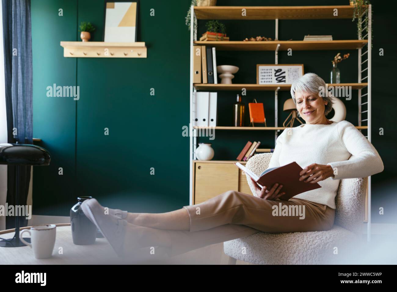 Donna matura leggere libro a casa Foto Stock