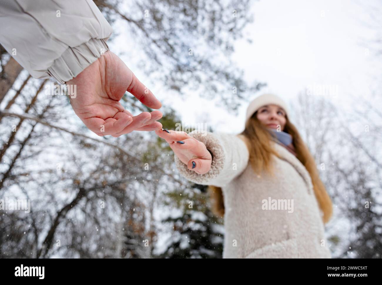 Giovane donna che raggiunge la mano dell'uomo al parco invernale Foto Stock