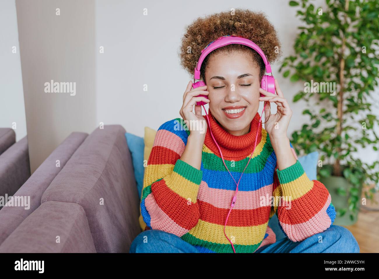 Donna felice ascoltando la musica attraverso le cuffie Foto Stock