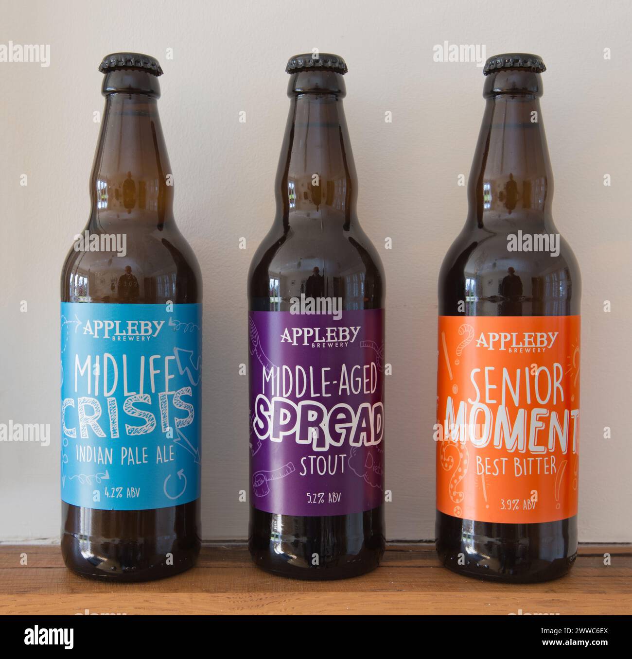 Preferirebbe una diffusione di mezza età a una crisi di mezza età? Bottiglie di birra Appleby sapientemente etichettate in fila. Foto Stock