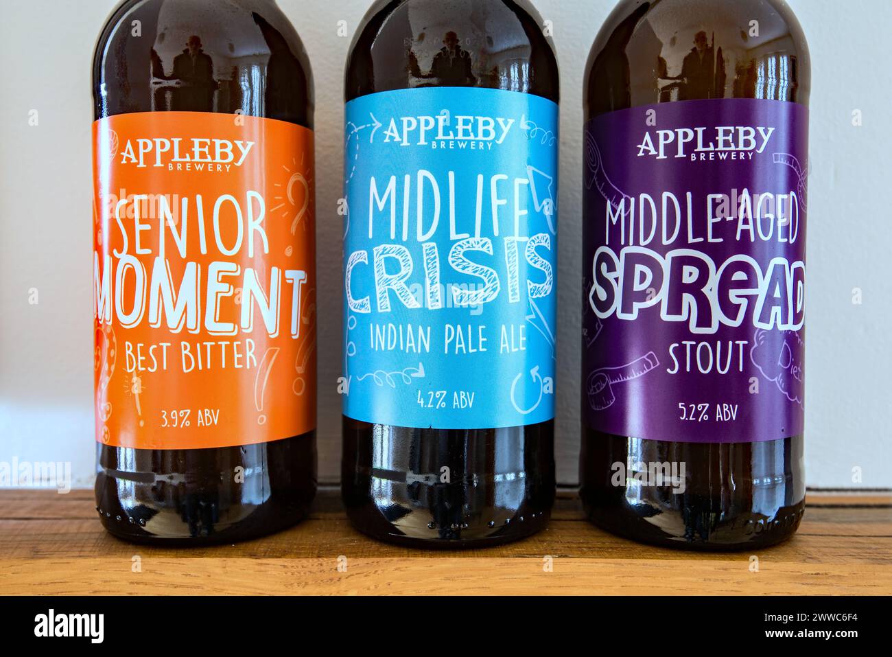 Preferirebbe una diffusione di mezza età a una crisi di mezza età? Bottiglie di birra Appleby sapientemente etichettate in fila. Foto Stock