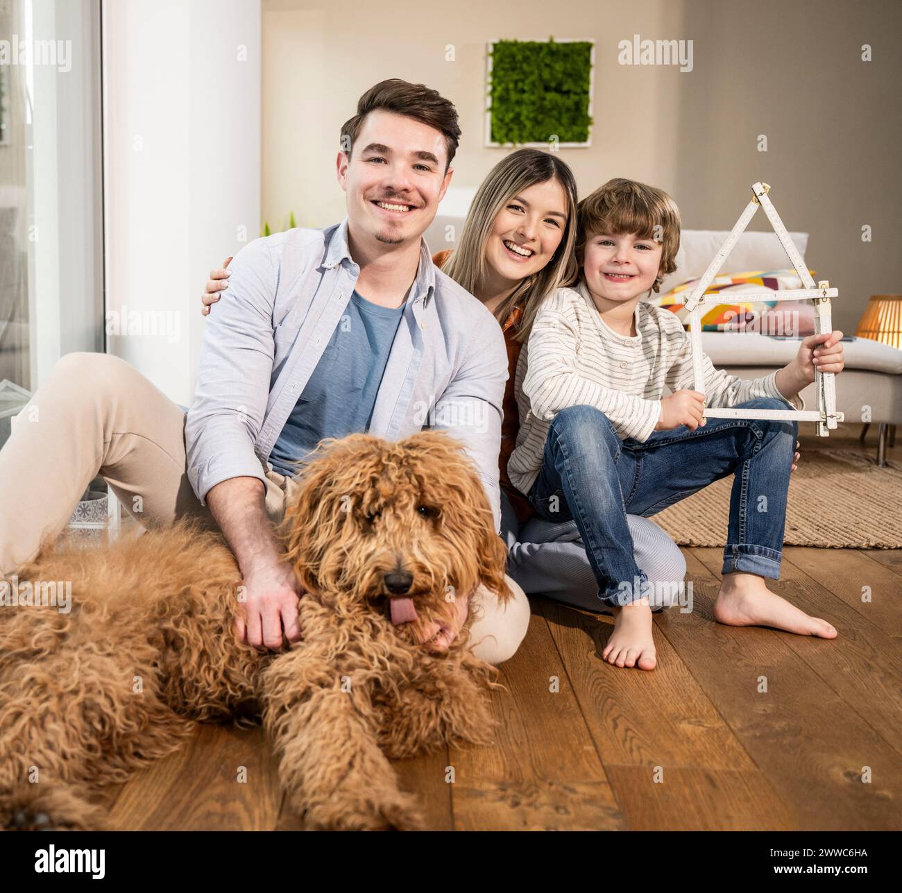 Famiglia felice con casa modello e cane a casa Foto Stock
