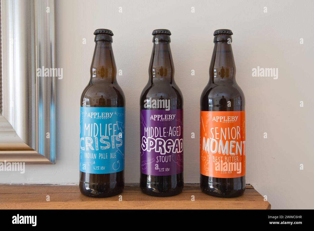 Preferirebbe una diffusione di mezza età a una crisi di mezza età? Bottiglie di birra Appleby sapientemente etichettate in fila. Foto Stock