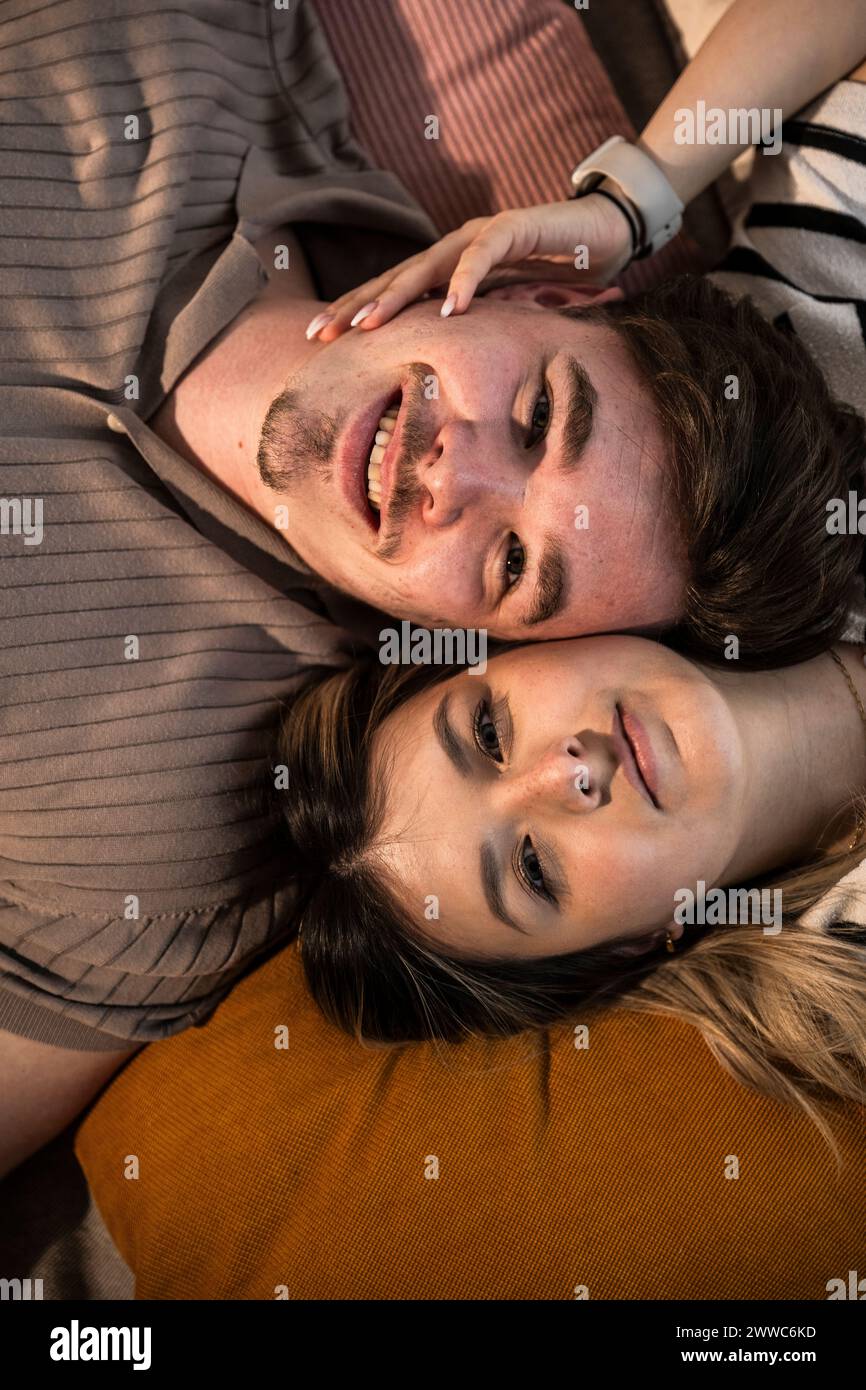 Sorridente giovane coppia sdraiata sui cuscini Foto Stock