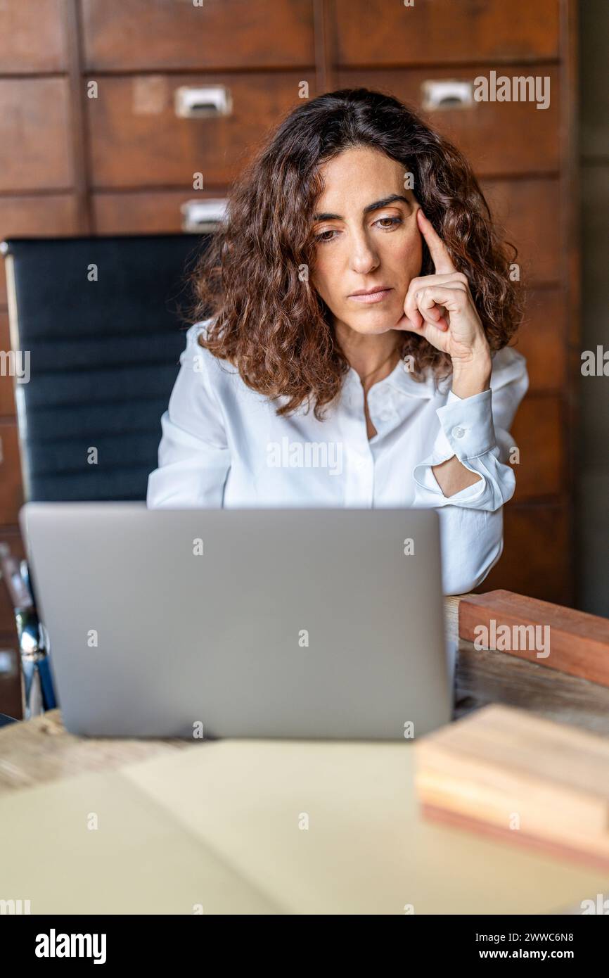 Businesswoman matura che lavora su laptop in ufficio Foto Stock