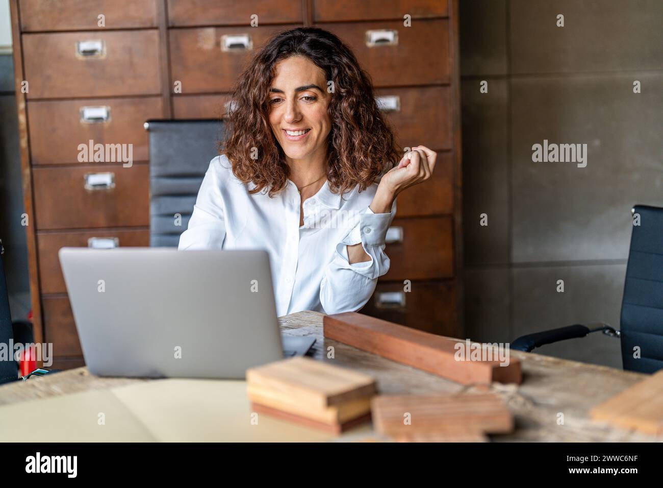 Donna d'affari sorridente che lavora su un notebook in ufficio Foto Stock