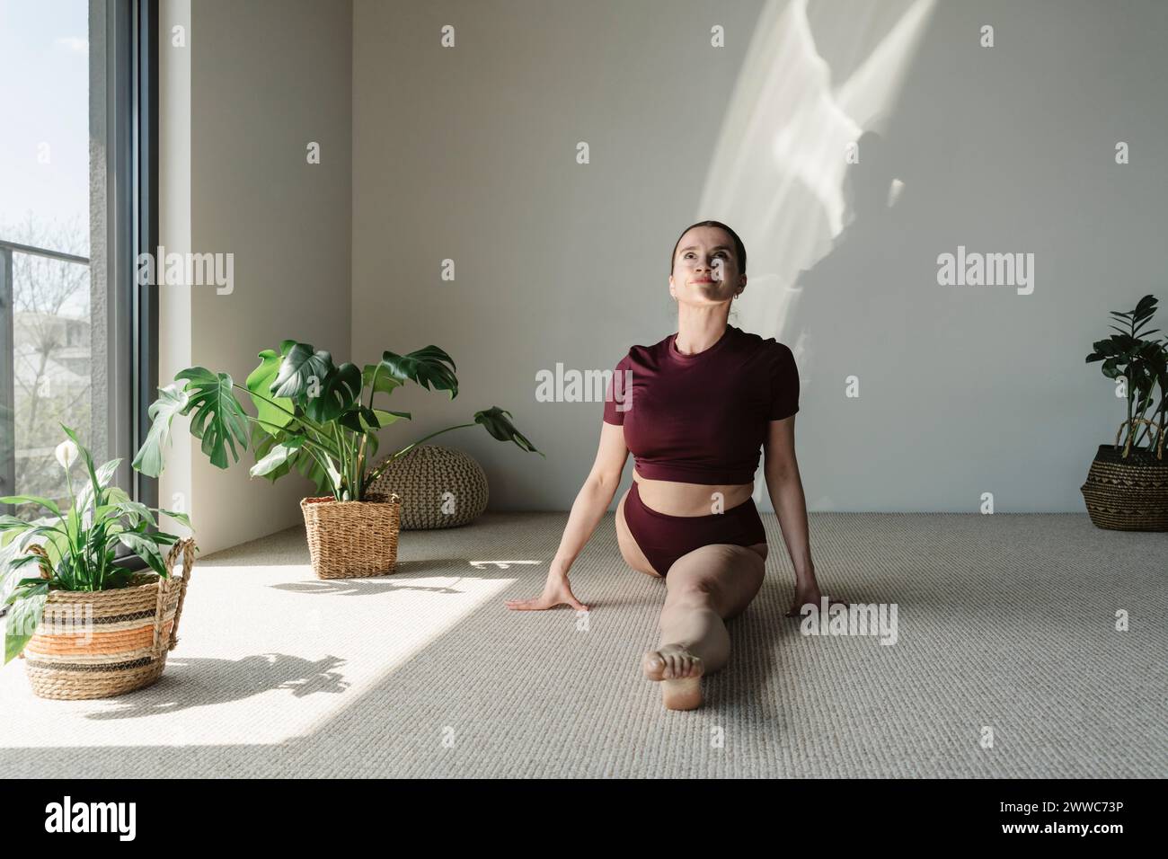Donna flessibile che si allena su un tappeto a casa Foto Stock