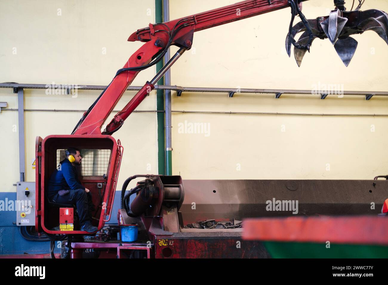 Meccanico seduto nella macchina gru in officina Foto Stock