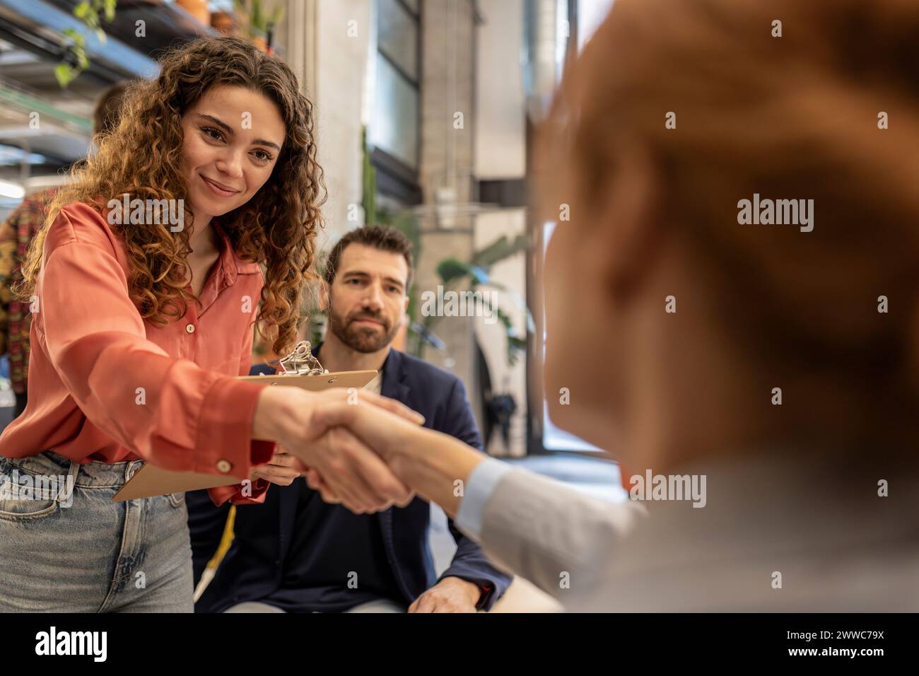 Reclutatore sorridente che fa stretta di mano con il candidato in ufficio Foto Stock