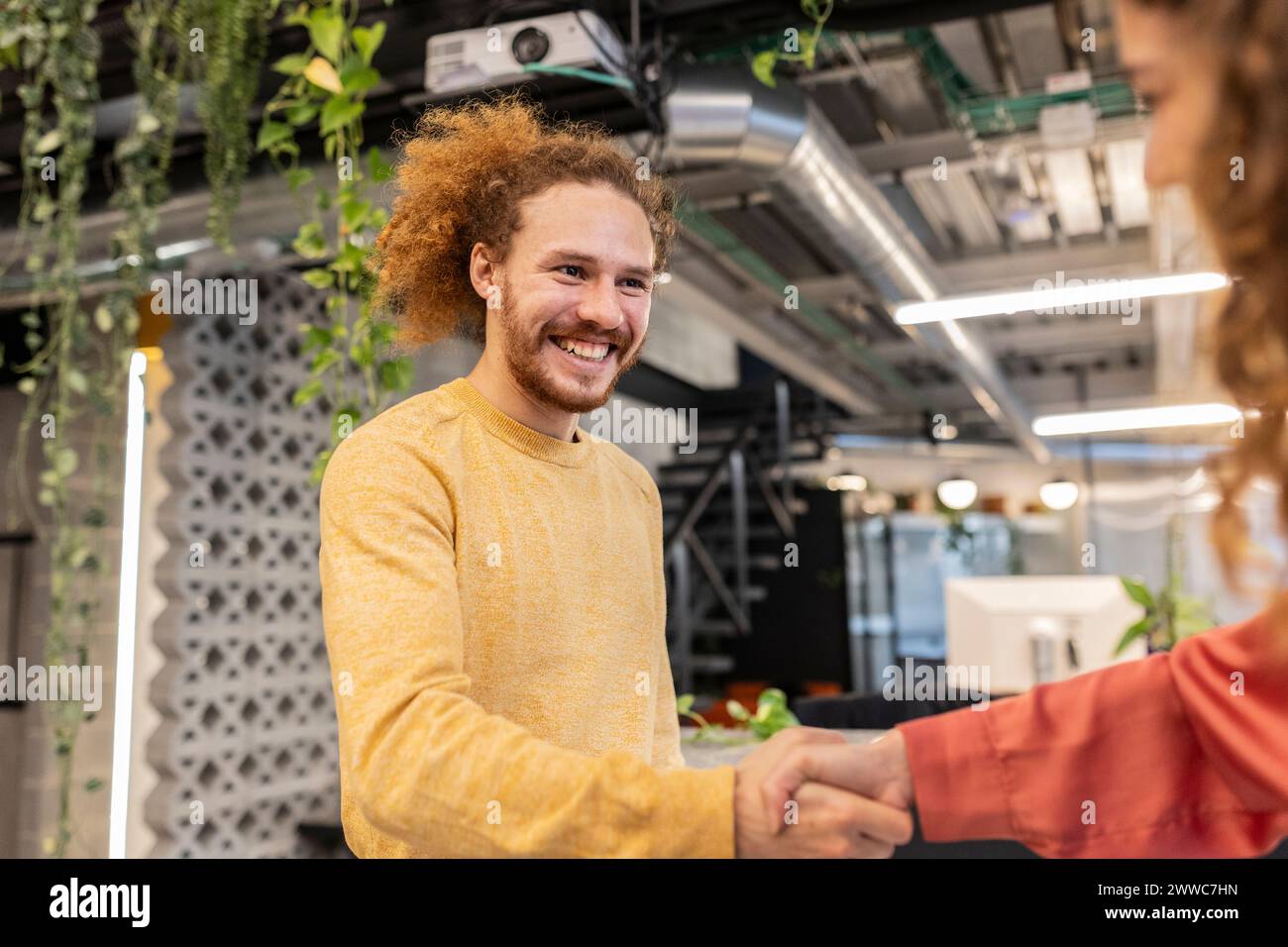 Un collega felice che fa stretta di mano con il collega in ufficio Foto Stock