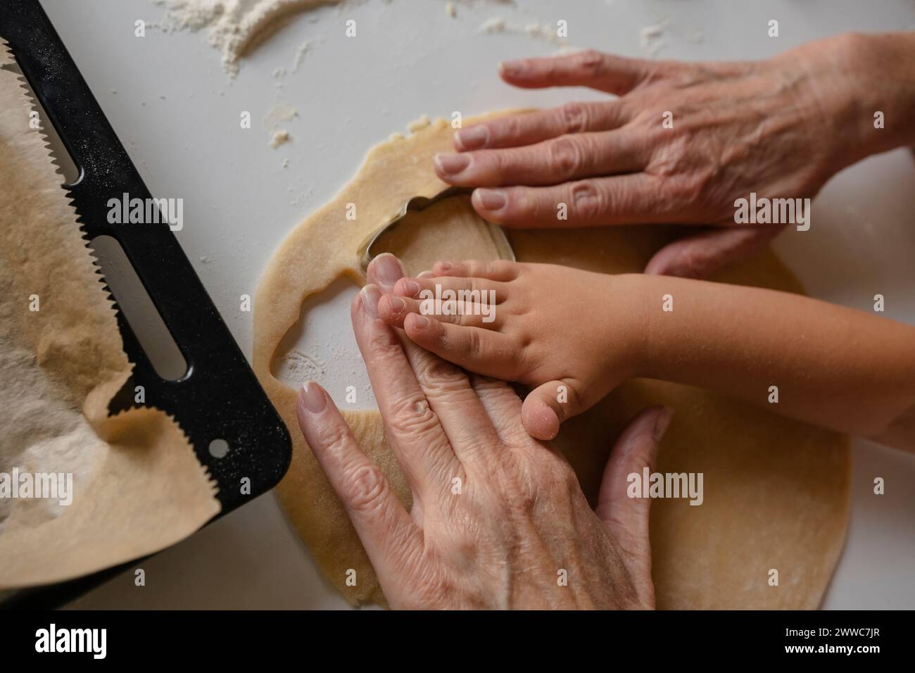 Il nipote e la nonna preparano i biscotti usando il taglierino Foto Stock