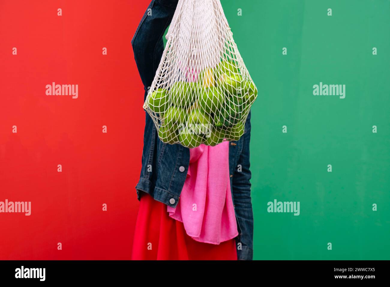 Donna che tiene un sacchetto di frutta davanti al muro Foto Stock