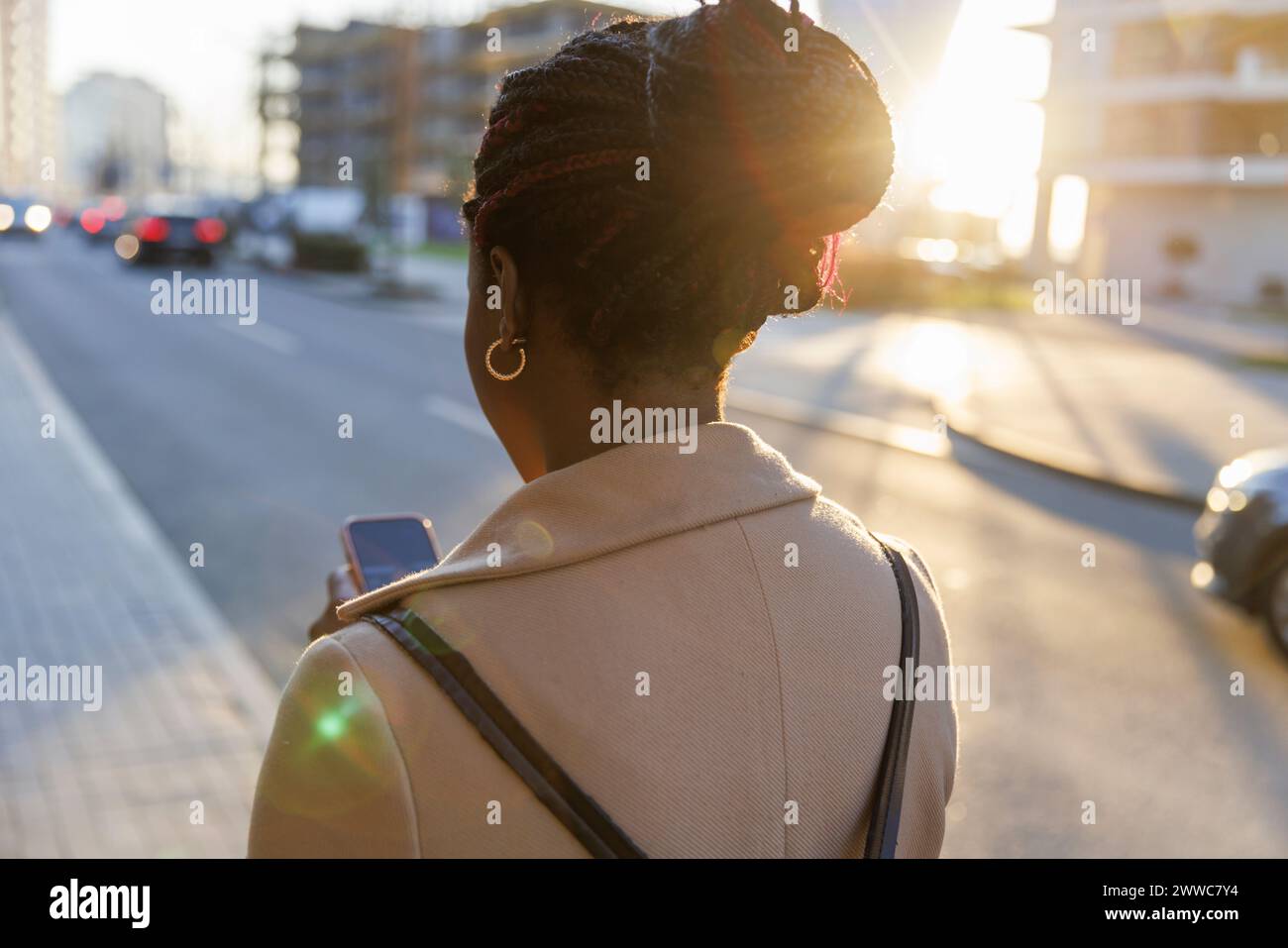Donna che usa il cellulare per strada al tramonto Foto Stock