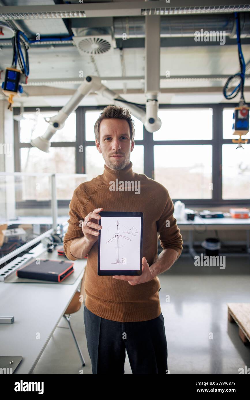 Ingegnere che mostra un tablet PC con uno schizzo della turbina eolica in esposizione in officina Foto Stock Ingegnere che mostra un tablet PC con uno schizzo della turbina eolica in esposizione in officina Foto Stock