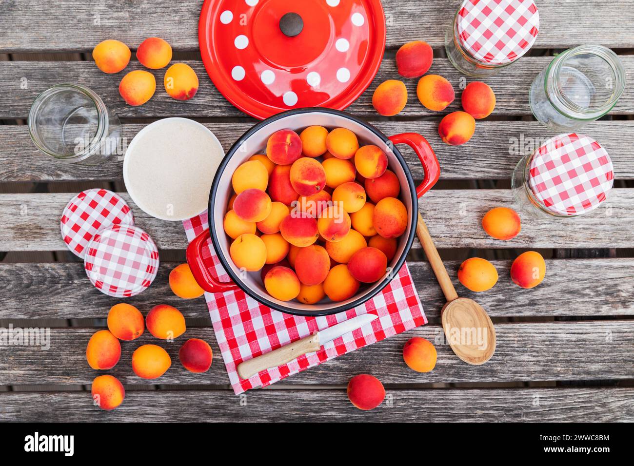 Preparazione della marmellata di albicocche su un tavolo da giardino in legno Foto Stock