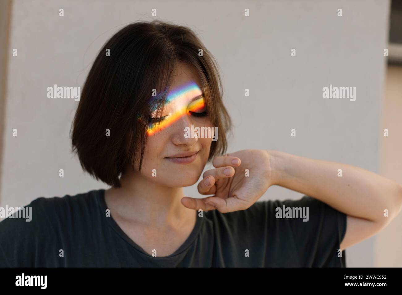 Donna con riflessi di luce color arcobaleno sul viso Foto Stock