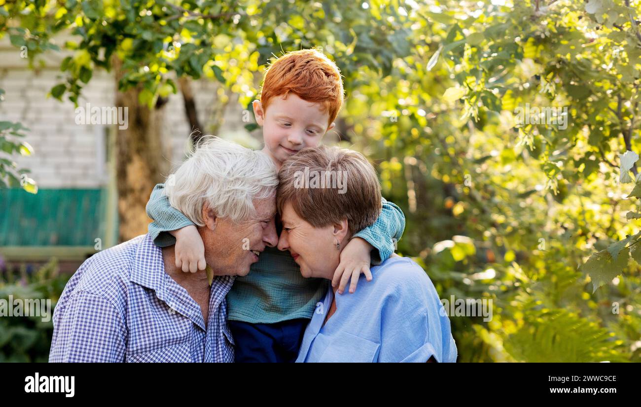 Felice coppia anziana con faccia a faccia vicino al nipote in giardino Foto Stock