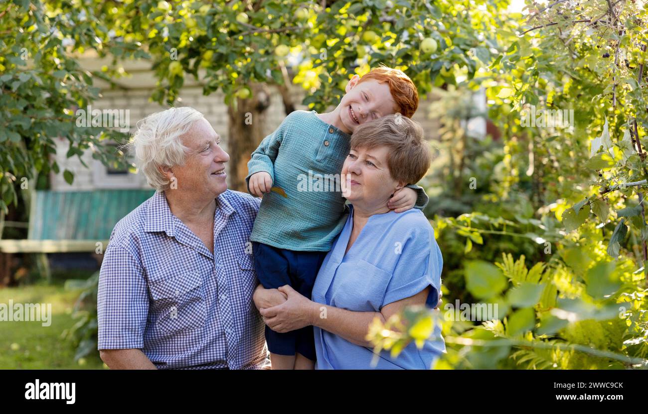 Ragazzo felice che si diverte con i nonni in giardino Foto Stock