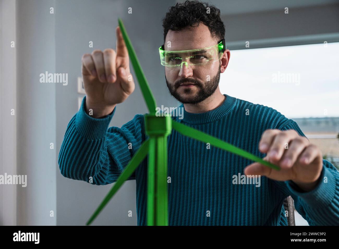 Architetto che indossa occhiali intelligenti ed esamina il modello di turbina eolica a casa Foto Stock Architetto che indossa occhiali intelligenti ed esamina il modello di turbina eolica a casa Foto Stock