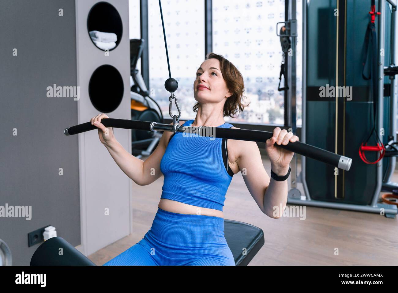 Donna matura che fa esercizio su una macchina laterale per il sollevamento in palestra Foto Stock