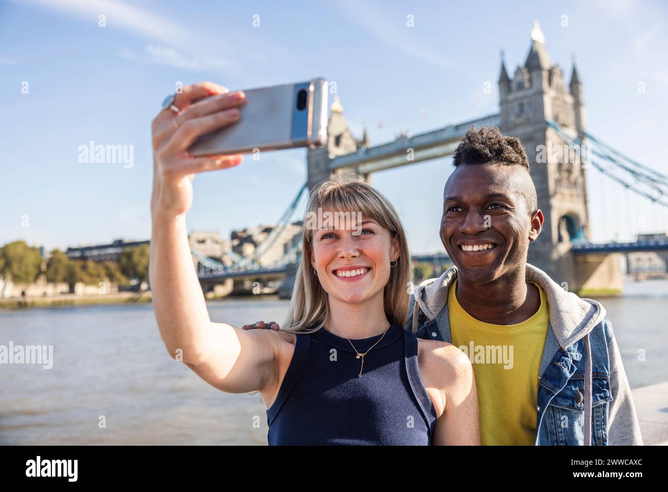 Donna sorridente che scatta selfie tramite smartphone con un amico in vacanza Foto Stock Donna sorridente che scatta selfie tramite smartphone con un amico in vacanza Foto Stock