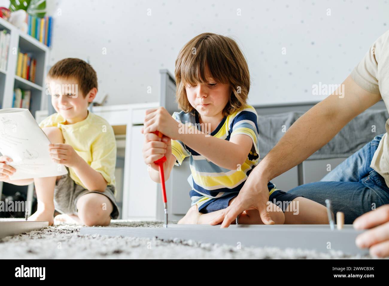 Bambino che stringe la vite con un cacciavite a casa Foto Stock