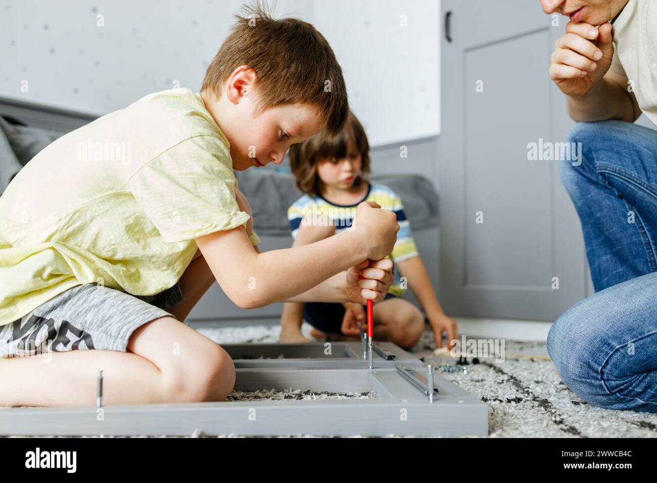 Ragazzo che stringe la vite sul comodino a casa Foto Stock