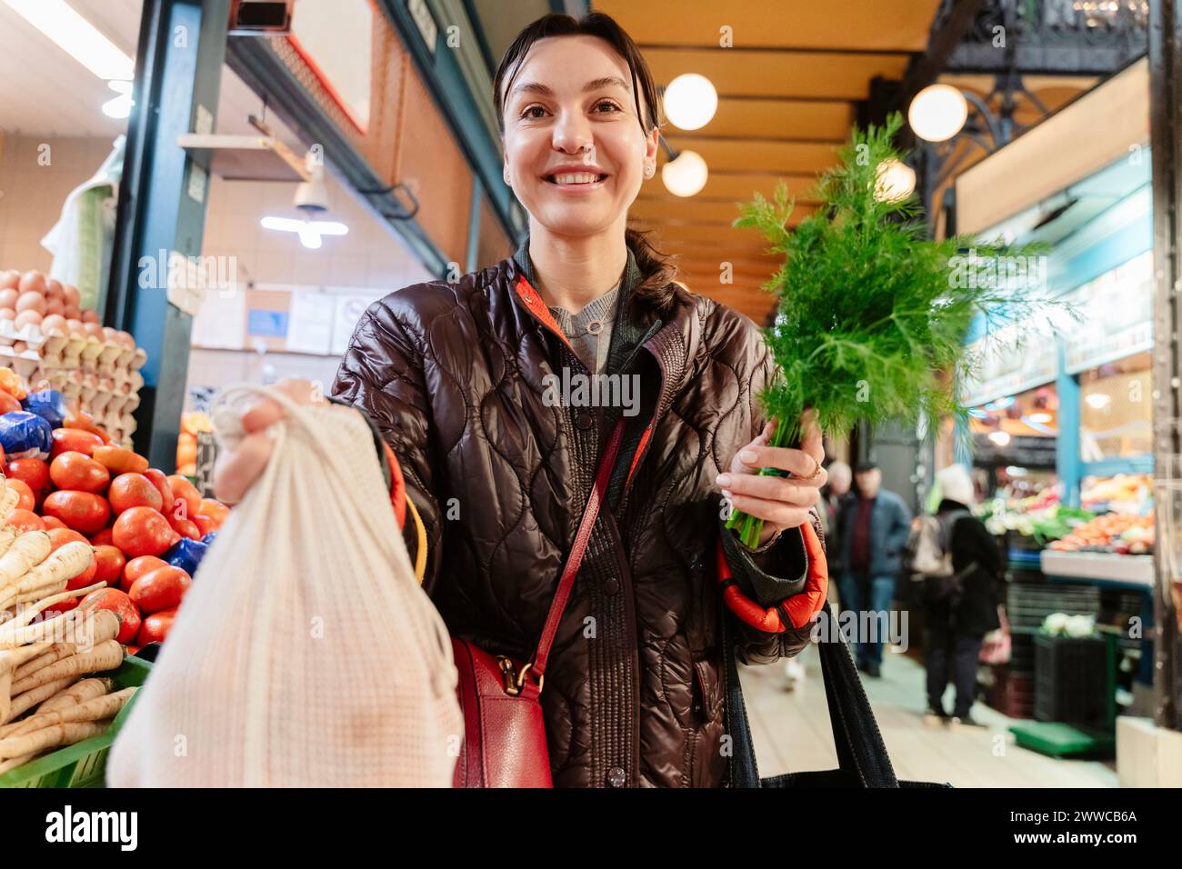 Donna felice che compra generi alimentari sul mercato Foto Stock